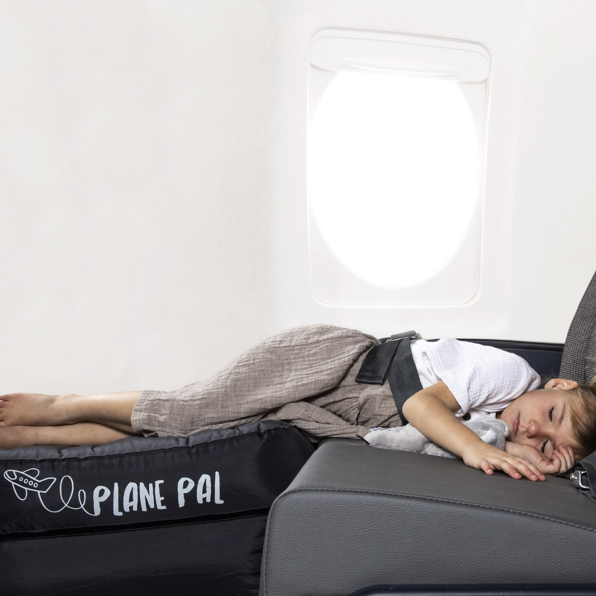 Child sleeping on Plane Pal inflatable travel bed for kids in airplane seat, comfortable journey
