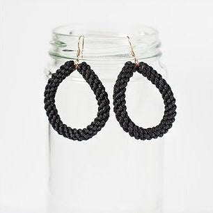 Black braided teardrop earrings displayed on a clear glass jar, minimalist style jewelry